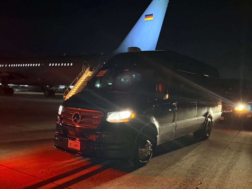 Luxury Mercedes-Benz Sprinter van from Haas Limo awaits airport transfer near a departing airplane, ensuring