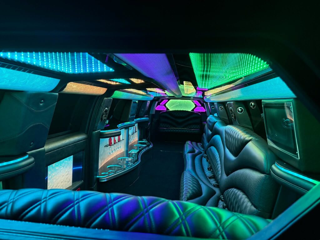Cadillac Escalade Stretch Limo interior with custom leather seating, fiber-optic lighting, refreshment bar, and flat-screen